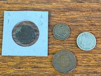 Five coins laid out: Canadian large cent in flip, 1941 Newfoundland cent, 1912 US Liberty nickel, 1853 Bank of Upper Canada token