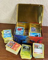 Lunch tin open with cards inside and surrounding stacks