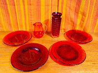 Group view of four red plates, tall vase, and mini jug