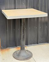 Full view of table showing square top, pedestal column and round base
