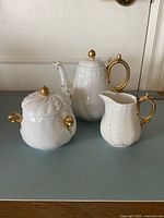 Full view of the three-piece porcelain set showing teapot, sugar bowl and creamer