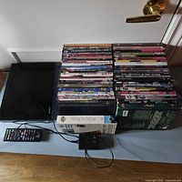 Sony DVD/Bluetooth player with stack of DVDs, remote and power adapter