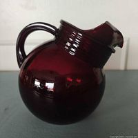 Full side view of ruby red glass ball pitcher with handle and ice lip