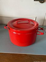 Red enamel pot with lid in place, side handles visible