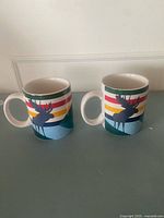 Front view of both mugs showing moose graphic and stripes