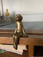Front-left view of brass frog sitting on shelf edge
