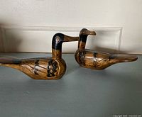 Both carved wooden duck figurines side view
