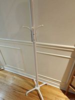 Full view of white metal coat rack showing pole and base