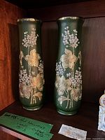 Both green enamel floral vases on shelf