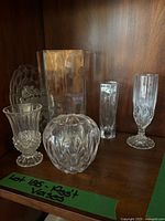 Group of five clear vases on shelf