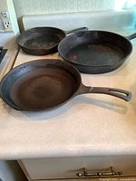 Three cast-iron frying pans showing wear