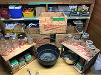 Group shot of crates, canning pot, jars, lid boxes, funnel and tongs