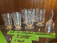 Eight pieces of etched crystal glassware on shelf