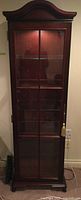 Full front view of closed curio cabinet showing arched top and glass door