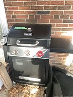 Front and side view of Dyna-Glo black three-burner grill with side shelf
