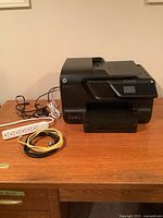 Printer, power bar and cables on desk, full view