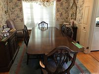 Extended mahogany dining table with chairs around it