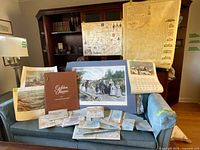 Overview of lot on couch: Golden Leaves booklet, art print, calendar, multiple folded maps, two wall maps displayed