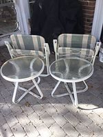 Two folding chairs laid flat behind two round side tables