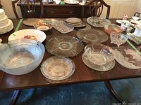 Overview of assorted glass platters, bowls and trivets on dining table
