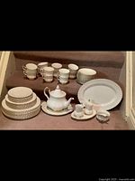All china pieces arranged on stairs showing plates, cups, platter, teapot, creamer, sugar