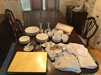 Overview of stacked Royal Doulton Richelieu china place settings, cups, serving pieces and candleholders on dining table