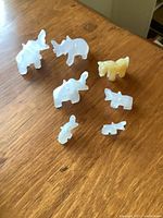 Seven carved translucent stone rhinoceros figurines on wood surface