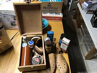 Open wooden box with shoe care contents and wooden shoe stretchers visible