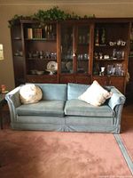 Front view of blue-grey two-seat sofa with two floral pillows.