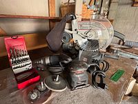 Group view showing Craftsman miter saw, Craftsman drill, Black & Decker sander, drill bits, spare blade, abrasive discs