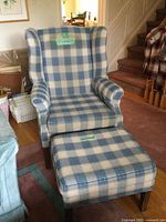 Front angle of wingback chair and ottoman showing plaid upholstery and wooden legs