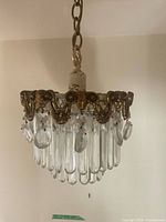 Close view of pendant showing brass frame and glass prisms