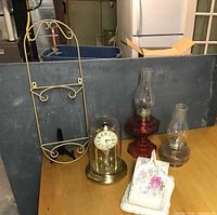 All items on table: plate holder, anniversary clock, two oil lamps, cheese dish