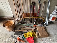 Group shot of all yard tools leaning against wall with accessories on floor