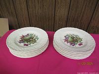 Twelve stacked Alfred Meakin fruit design plates on table