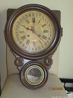 Front view of E. Ingraham Dew Drop calendar wall clock showing dial and lower pendulum window
