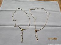 Both gold-tone slide chain necklaces laid flat showing overall length and design