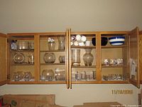 Cabinet view showing entire assortment of clear glass vases, bowls, candle holders and tumblers