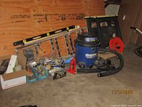 Overall group of tools: Shop-Vac, ladder section, level, saw horses, jack, hand tools, plywood