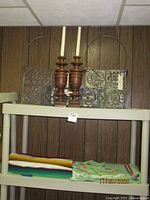 Serape, table linens folded, wood candlesticks, and metal wall panels displayed on shelf