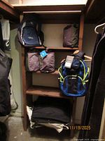 Shelf with multiple travel items: two backpacks, three packing cubes, garment bags folded