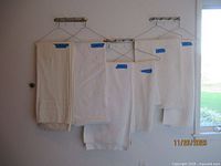 Five white table covers hanging with size labels