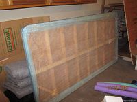 Wood twin bed board leaning against wall, slatted construction visible through plastic