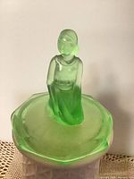 Front view of uranium glass jar lid with figurine