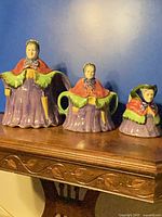 Full view of three figural ceramic pieces on shelf