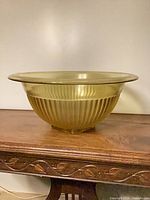 Side view of amber ribbed glass mixing bowl on wooden surface