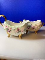 Creamer and sugar bowl together showing floral design and gold feet