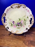 Full plate on stand showing scalloped rim, handles and floral design