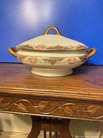 Front view of covered Limoges porcelain soup tureen on wooden surface
