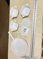 Group shot showing three casseroles, two lids and skillet with rulers for scale